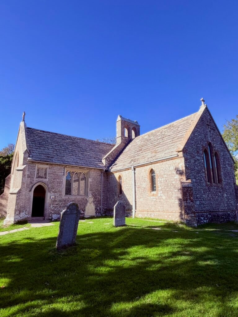 St Mary's Church in Tyneham, Dorset, with its stone walls, bellcote and churchyard gravestones