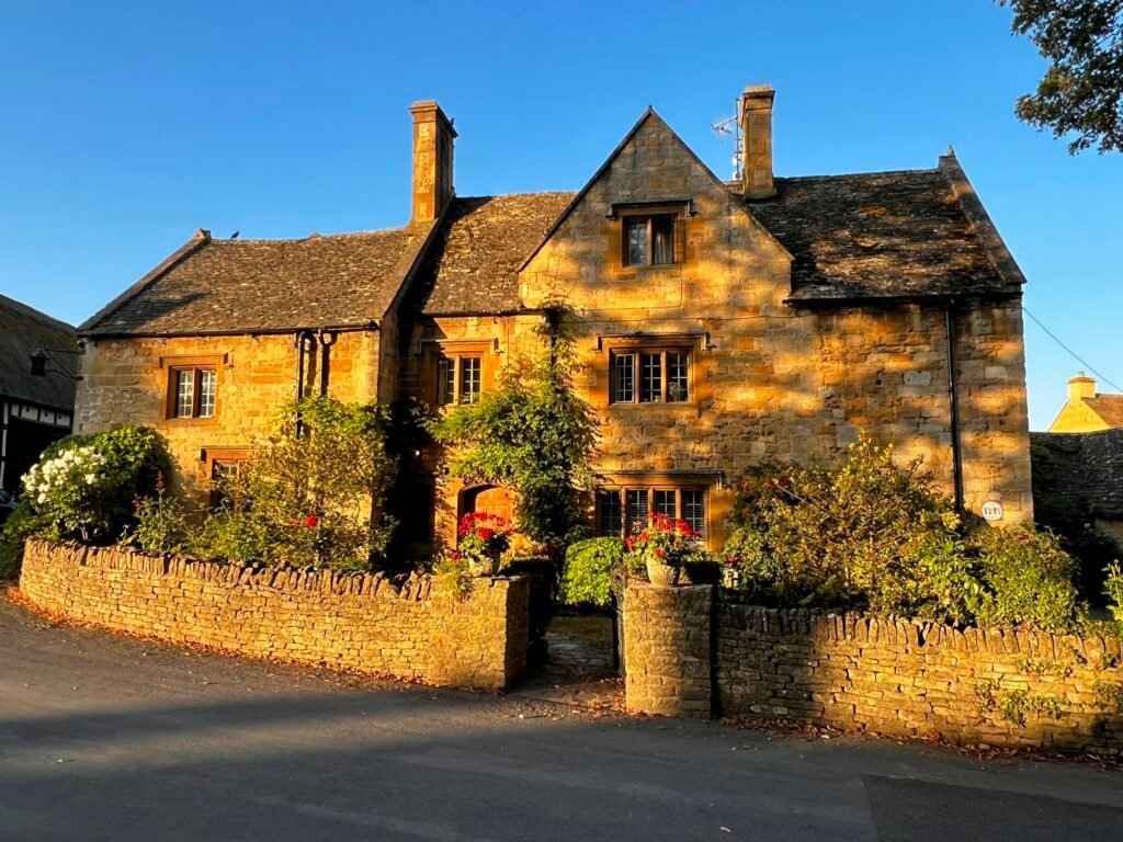 Golden morning sunlight on a traditional stone cottage in Stanton, Cotswolds