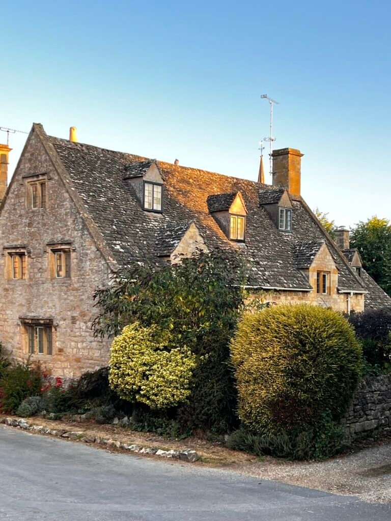 Large historic stone house in Stanton with tall windows and carefully clipped topiary
