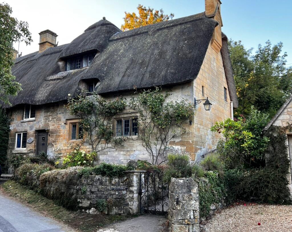 Traditional thatched cottage with stone walls and a cottage garden in Stanton