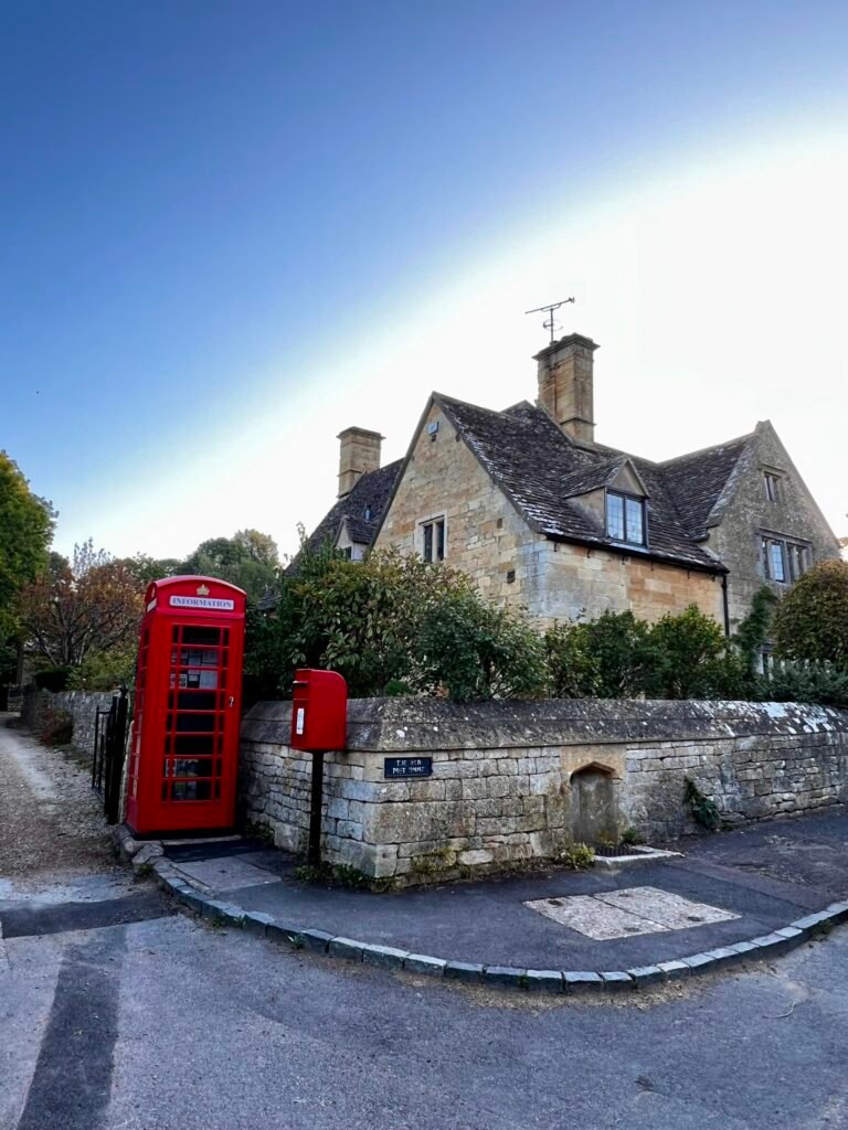Red telephone box used as a visitor information point beside the Old Post House in Stanton
