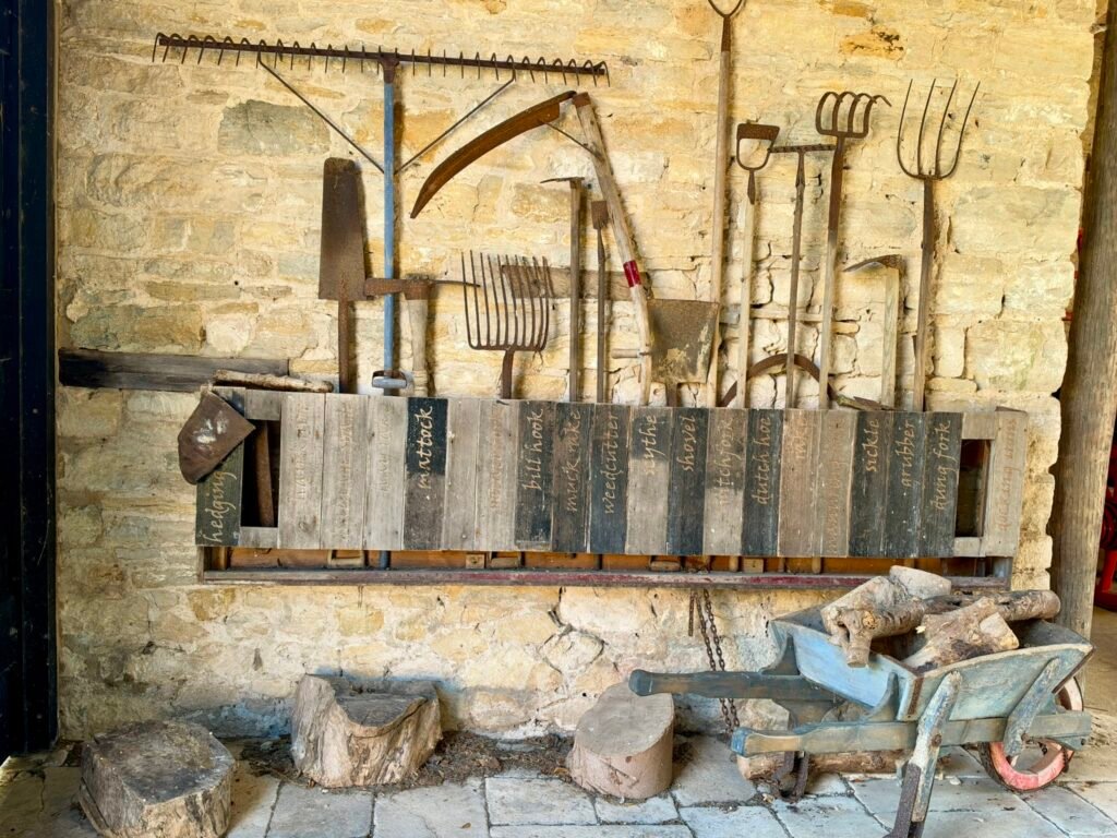 Traditional farming tools, shelves and a workbench inside a stone farm building at Tyneham