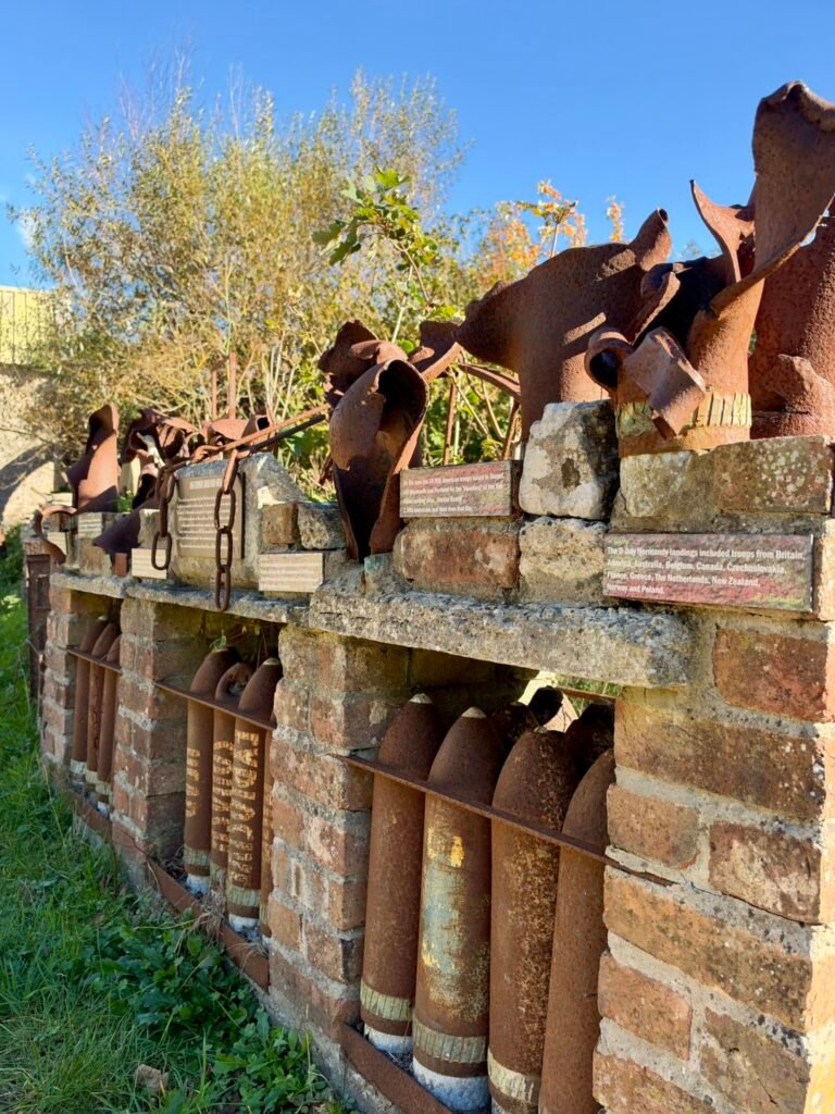 Rusting shell casings and military metal artefacts displayed on a brick wall at Tyneham, Dorset