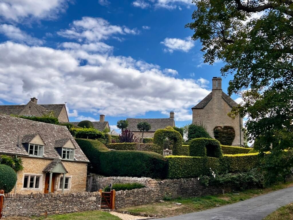 Golden stone cottages, clipped hedges and gardens in Upper Slaughter, Gloucestershire.