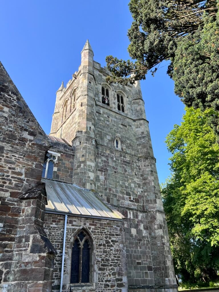Historic stone tower of Wimborne Minster against a blue sky